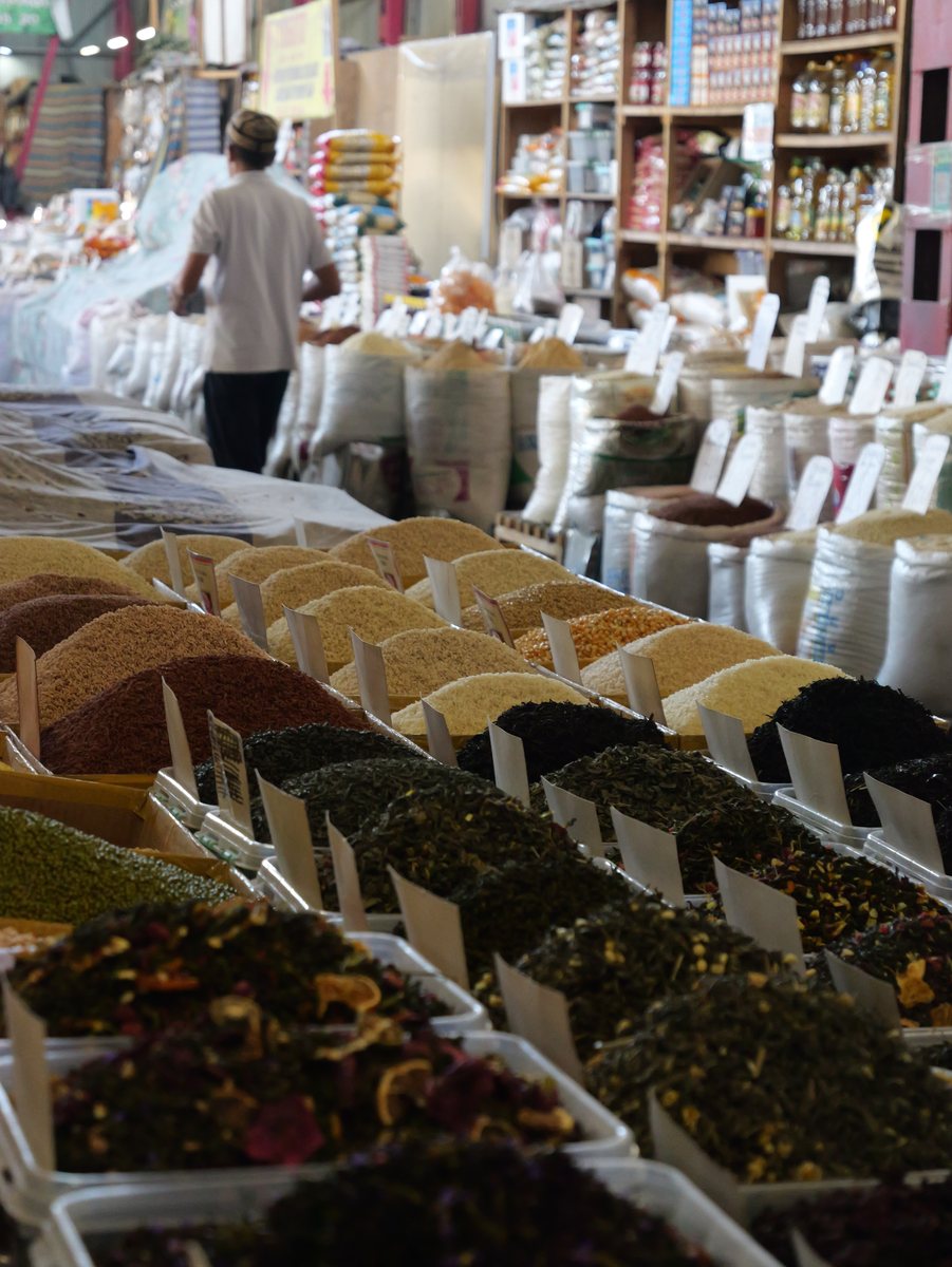 Marktstand mit Teesorten, Gewürzen und Säcken, Verkäufer im Hintergrund