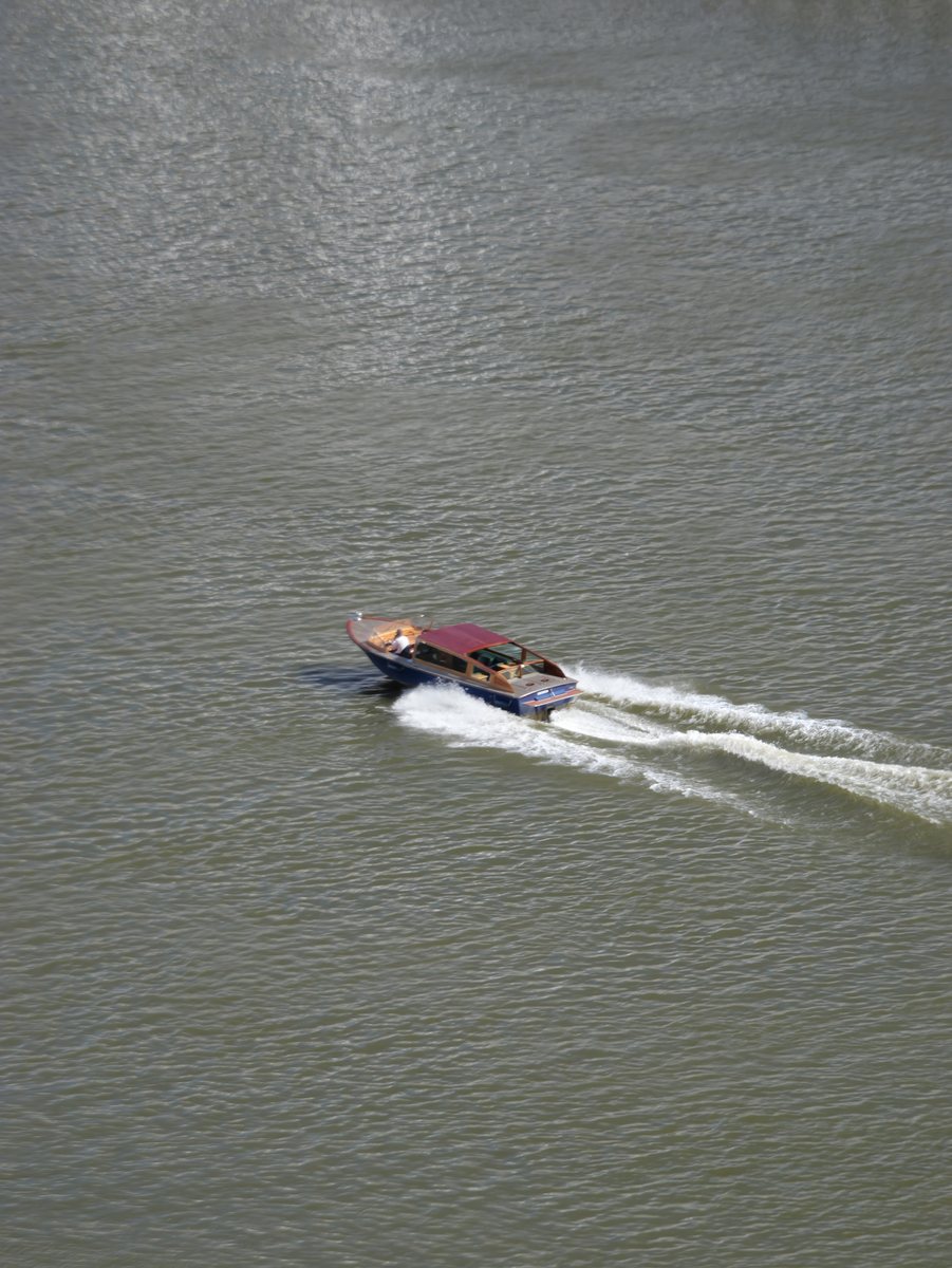 Motorboot von oben, zieht eine weisse Spur durch das graugrüne Wasser