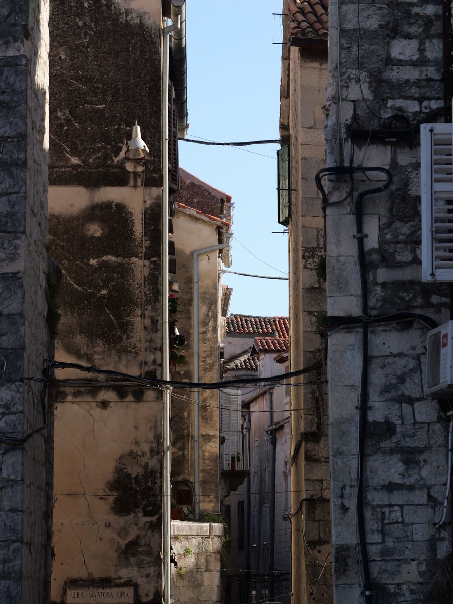 Enge Altstadtgasse zwischen hohen Steinhäusern, oben ein Streifen Himmel