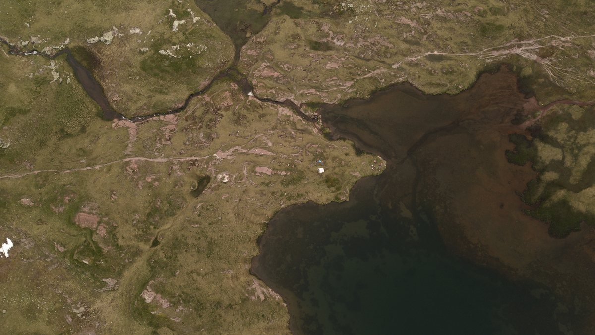 Luftbild eines Bachlaufs, der sich durch die Hochebene in einen Moorsee schlängelt