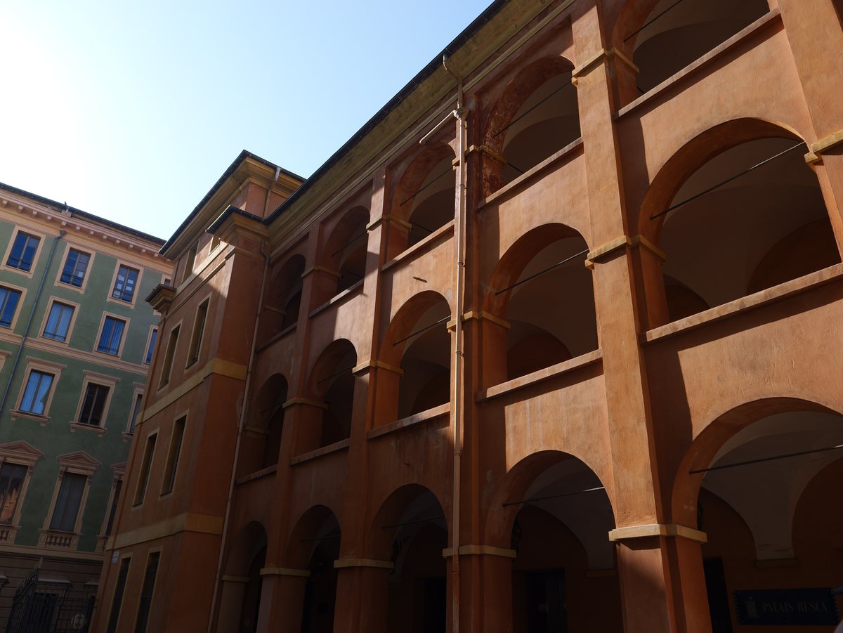 Ockerfarbene Bogengänge des Palais Rusca in Nizza vor blauem Himmel